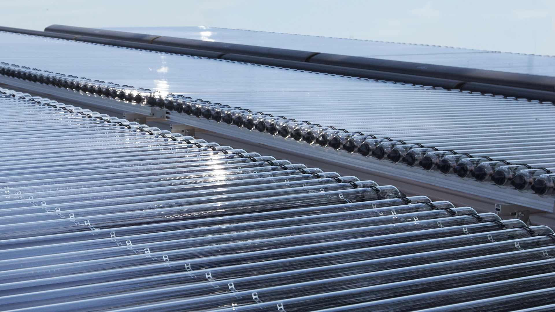 Nahaufnahme von Solarpanels mit Sonnenlichtreflexionen auf der Oberfläche in Reihen angeordnet mit Licht- und Schattenmuster